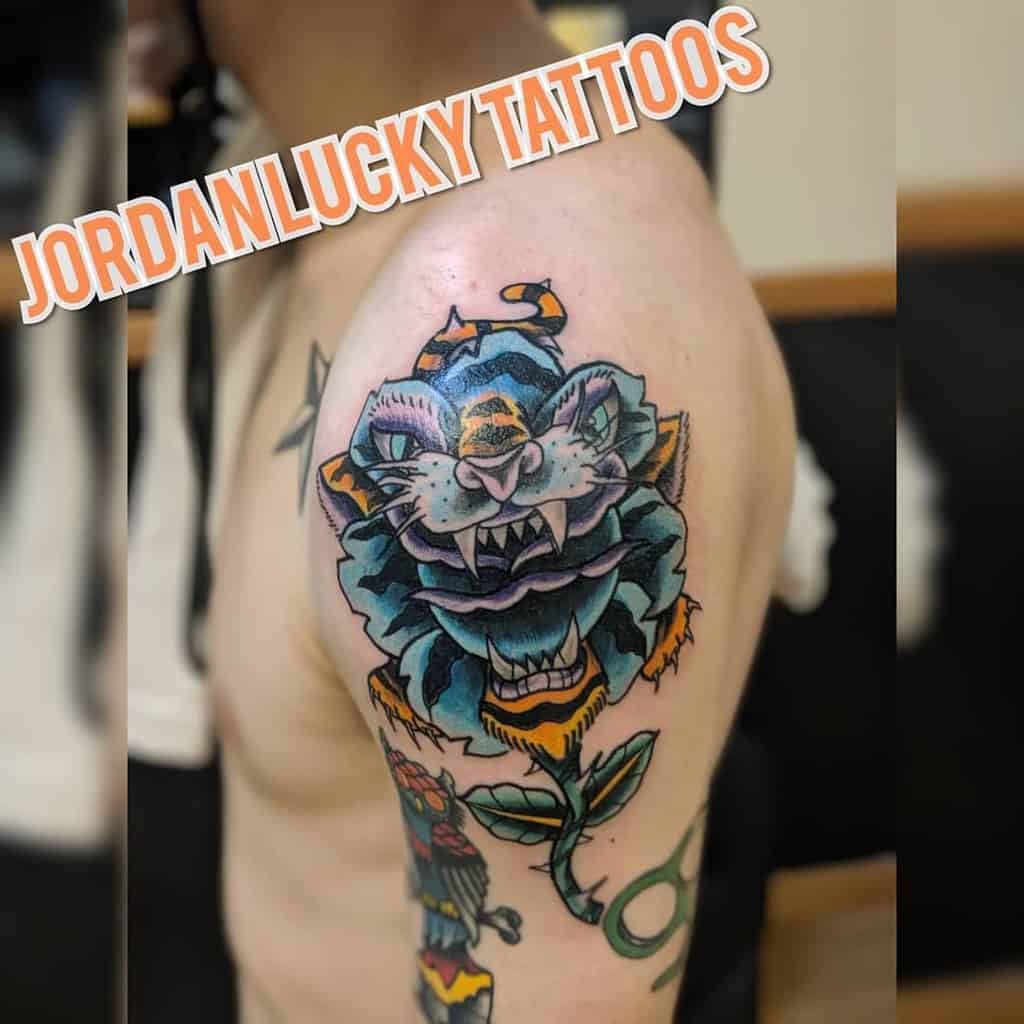 A striking arm tattoo features a fierce tiger head intertwined with a vibrant floral bouquet, captivating those who admire its bold design