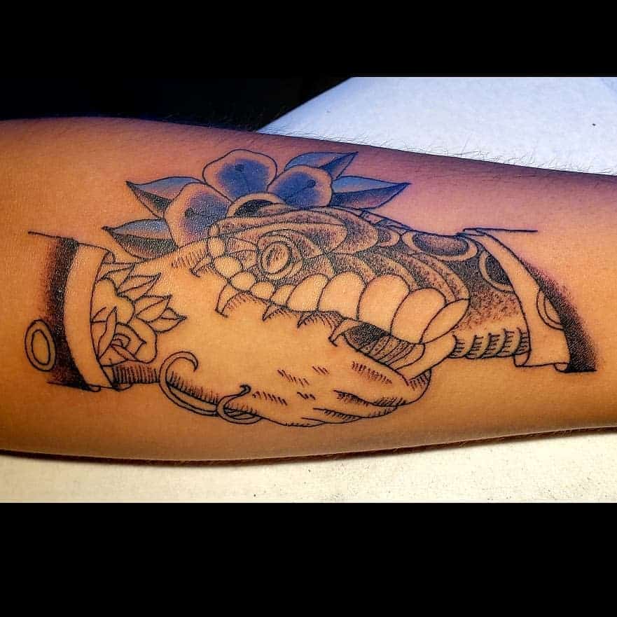 Tattoo of a handshake between a human and a snake, with a flower in the background