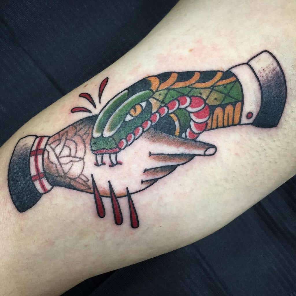 Vibrant traditional tattoo of a handshake with a snake coiled around, featuring bold colors and sharp detailing