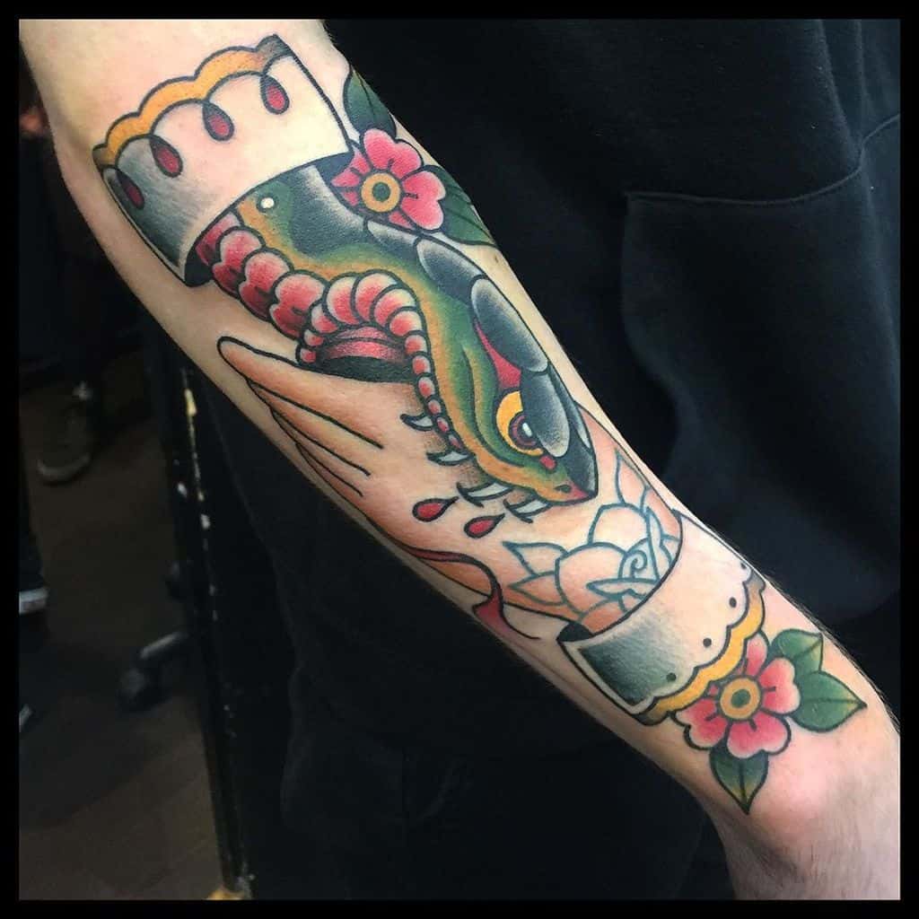 Traditional forearm tattoo with vibrant colors, featuring a handshake with a coiled snake and floral accents, symbolizing trust and caution
