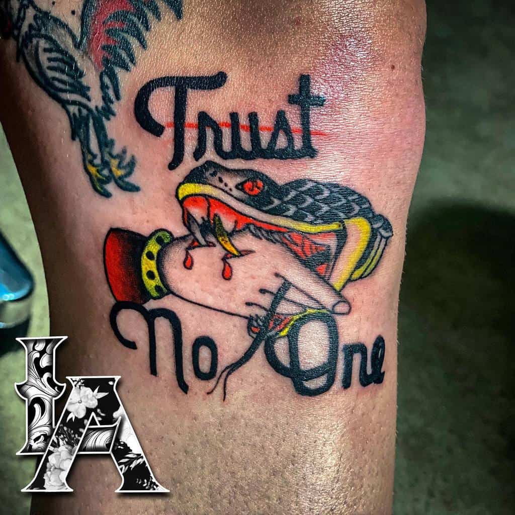 Tattoo of a snake biting a hand with the words "Trust No One" above and below