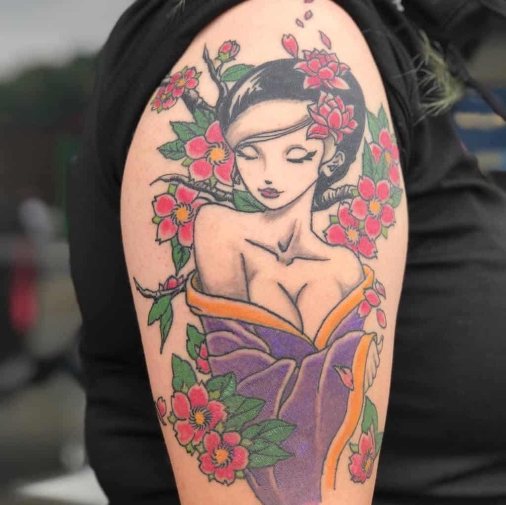 Tattoo of a woman in a kimono surrounded by pink flowers on an upper arm
