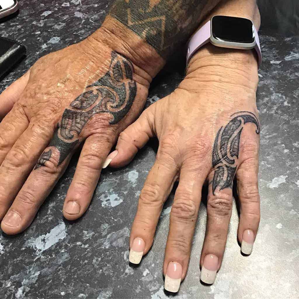 Two hands with black tattoos