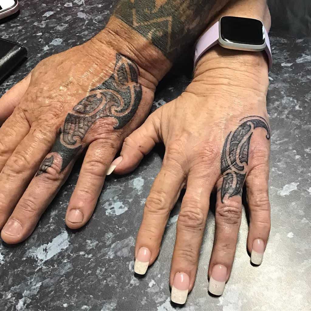 Matching tribal-style tattoos wrapping around the fingers, symbolizing unity and connection