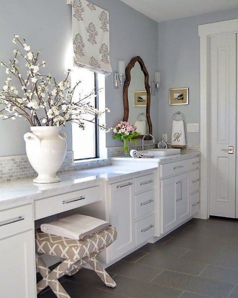 Traditional white vanity with marble countertop, floral decor, and vintage mirror.