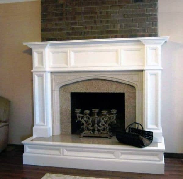 Traditional white fireplace with an arched opening, detailed mantel, and brick accent wall.
