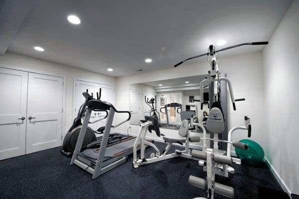 Cozy home gym with treadmills, stationary bikes, and weight machines in a small, white-walled room
