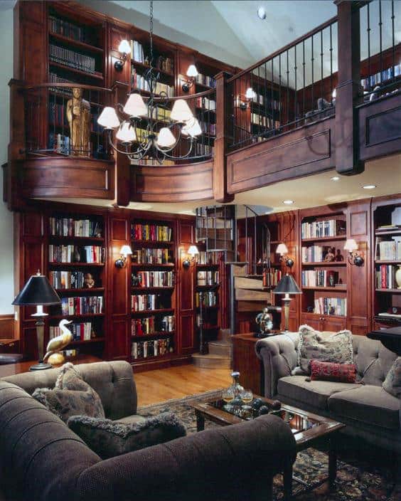 Cozy living room with bookshelves, a spiral staircase, sofas, and a chandelier under a high ceiling