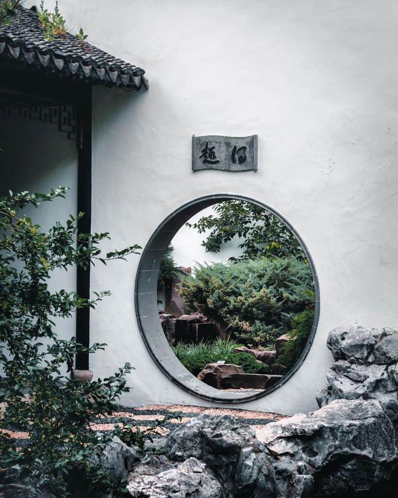 traditional japanese garden circular entryway through white wall 
