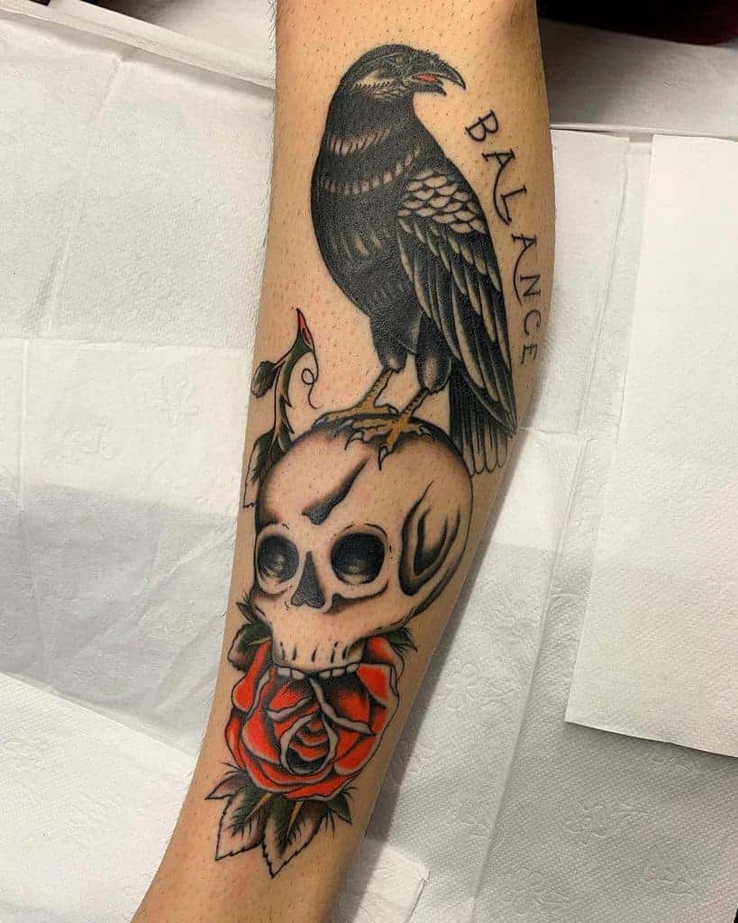 Tattoo of a raven perched on a skull with a red rose below and "BALANCE" text on forearm