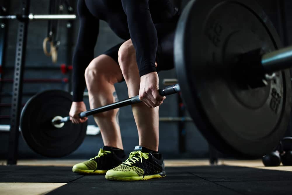 training barbell wearing black and yellow shoes