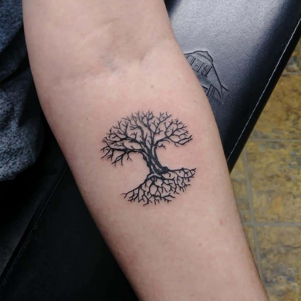 Simple black ink tattoo of a tree of life with roots, symbolizing balance and connection between earth and sky