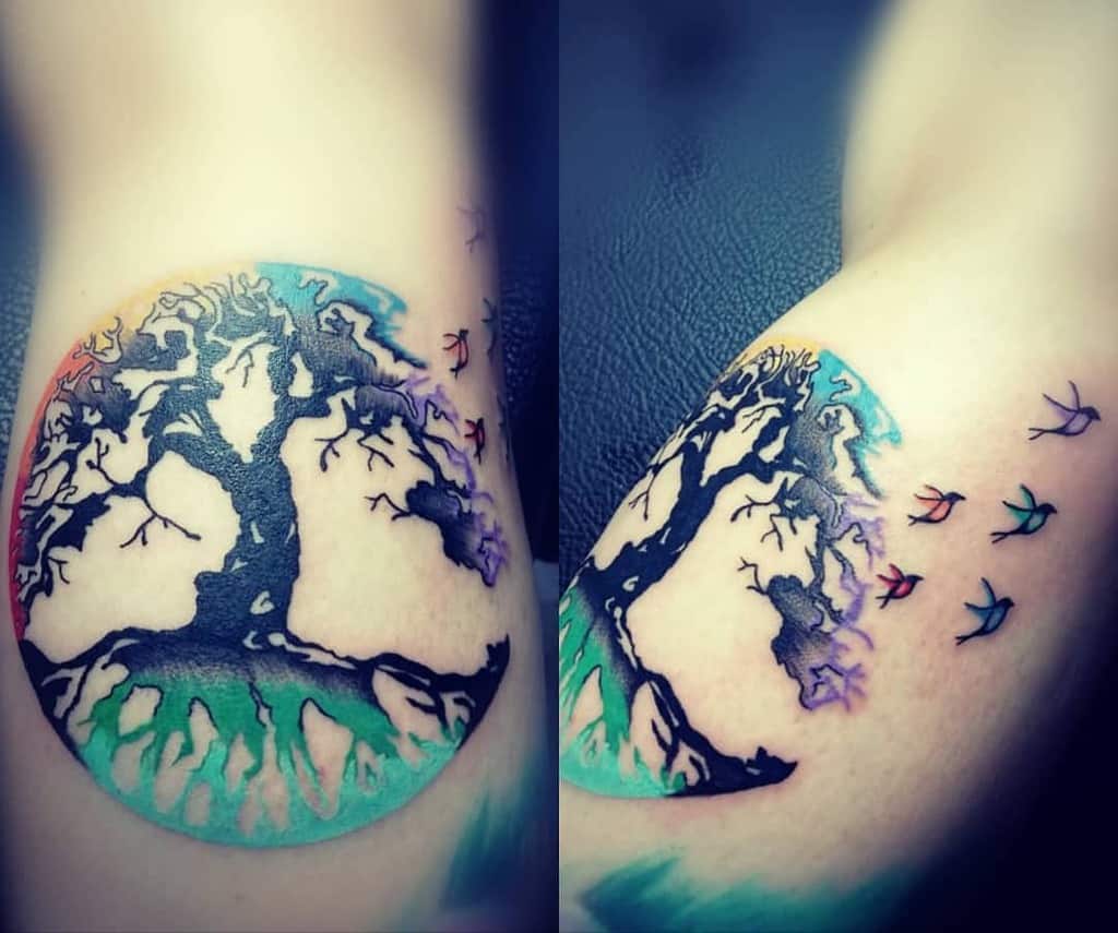 Vibrant tree tattoo featuring a gradient of colors and flying birds, symbolizing harmony between nature and freedom of the spirit