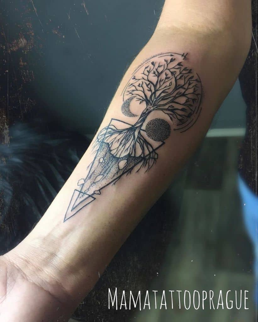 Delicate forearm tattoo featuring a balanced tree with roots and branches, symbolizing harmony and interconnectedness