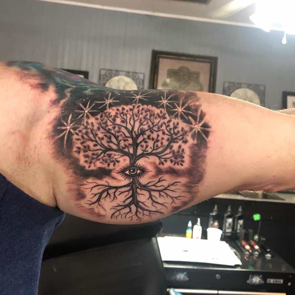 Tattoo of a tree with an eye in its trunk on a bicep, surrounded by stars