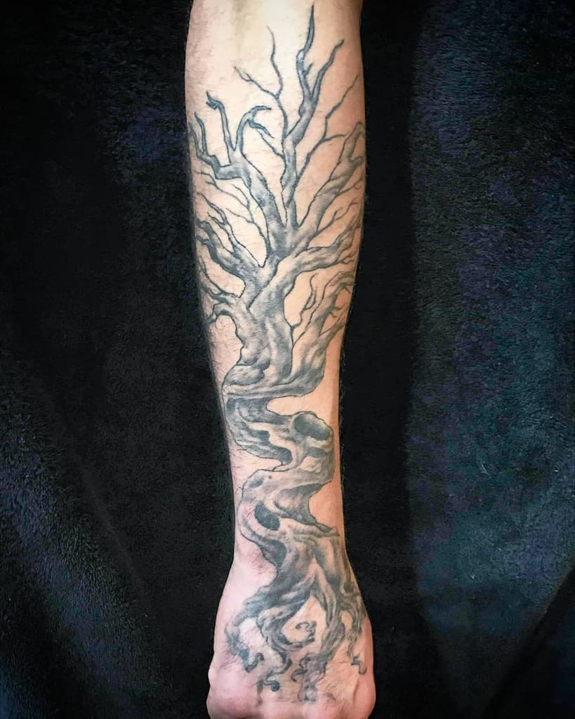 Black and gray twisted tree tattoo with flowing roots and branches, symbolizing resilience, growth, and the connection between life forces.