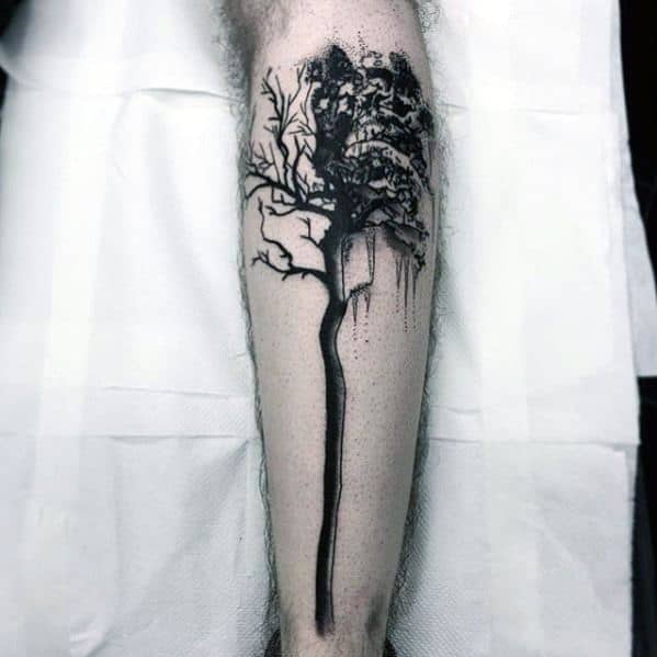 Black ink abstract tree tattoo on the leg, featuring a long, thin trunk with dripping ink effects and a dense canopy for a bold artistic design.