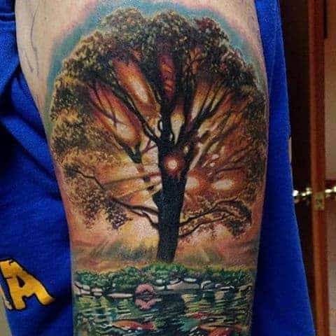 Tattoo of a tree with sunlight filtering through branches above a pond with koi fish