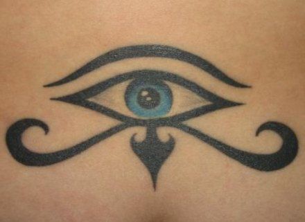 Tattoo of the Eye of Horus with a detailed blue iris, inked in black on the lower back.
