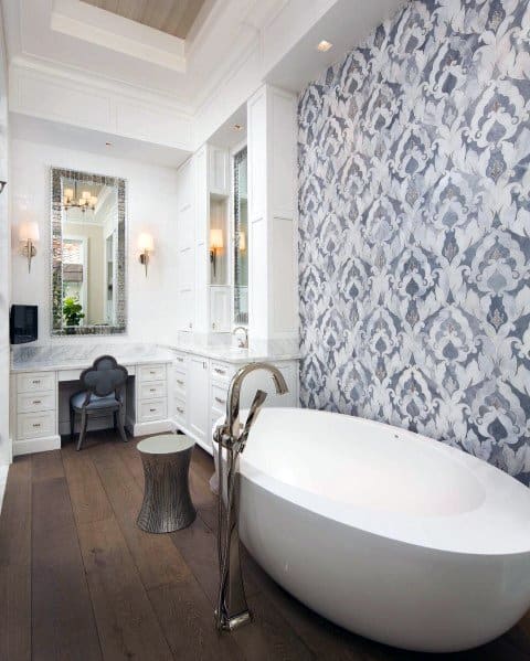 Elegant bathroom featuring a freestanding tub, trey ceiling with crown molding, and a stylish patterned wall, creating a luxurious ambiance