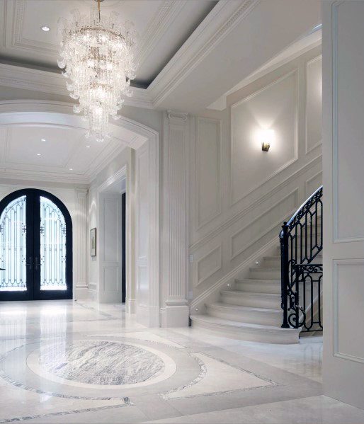 Grand foyer with a trey ceiling, ornate crown molding, and a stunning chandelier, highlighting the elegant marble flooring and staircase