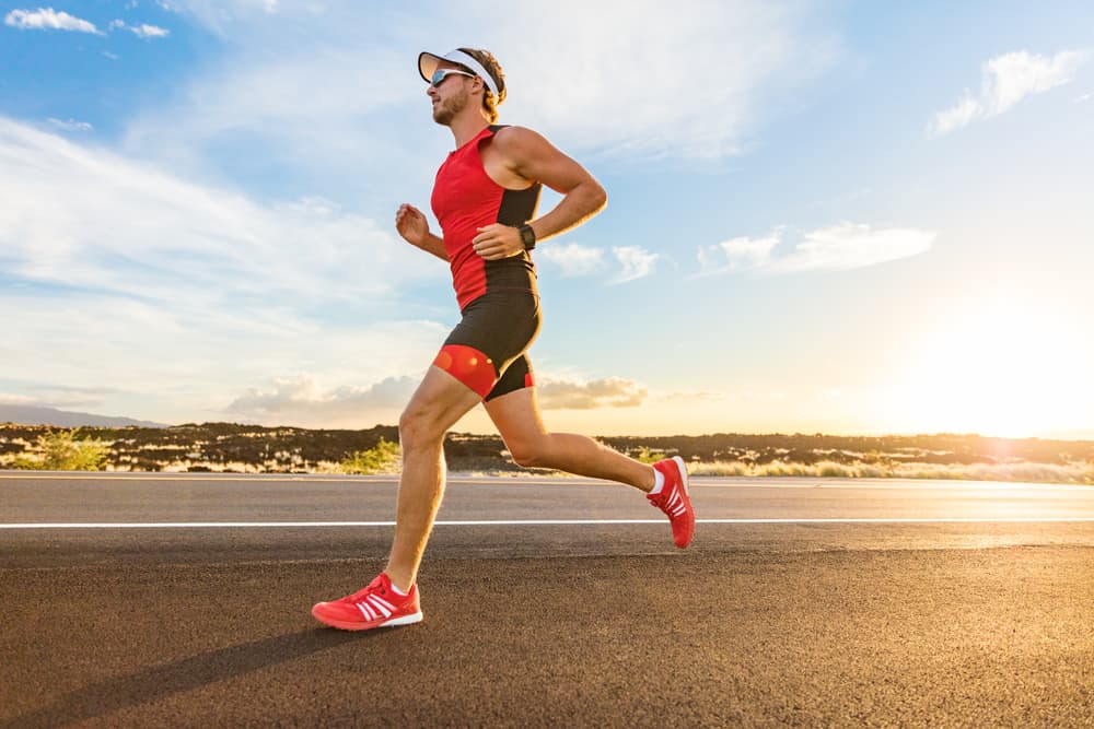 triathlete man running on road wearing red shoes