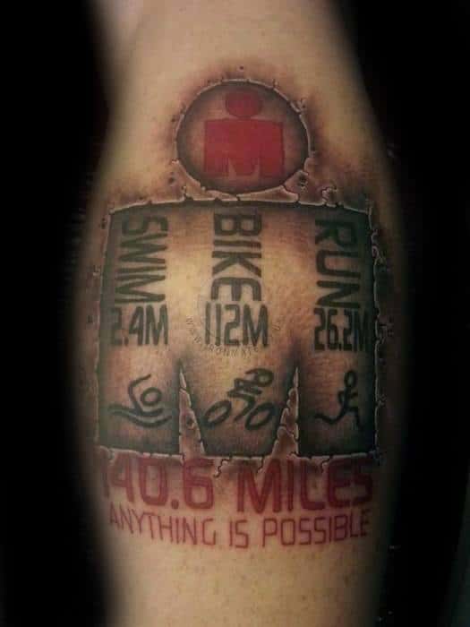 Tattoo depicting the Ironman logo, with distances for swimming (2.4 miles), biking (112 miles), and running (26.2 miles), along with the phrase "Anything is Possible" in bold lettering.