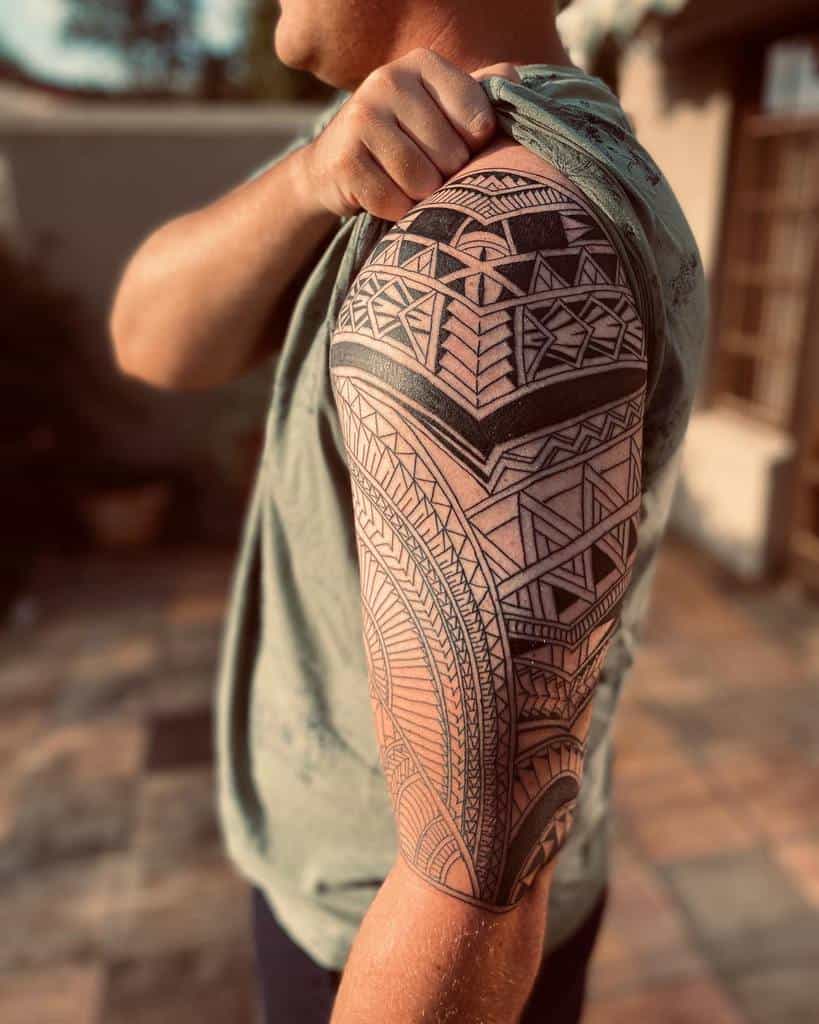 Man displaying a detailed Polynesian tattoo sleeve on his upper arm
