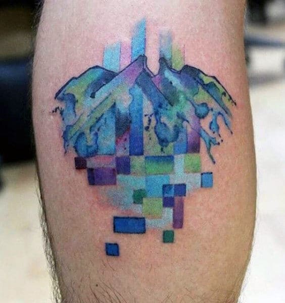 Colorful calf tattoo of abstract mountains blending into a pixelated digital design, with shades of blue, green, and purple