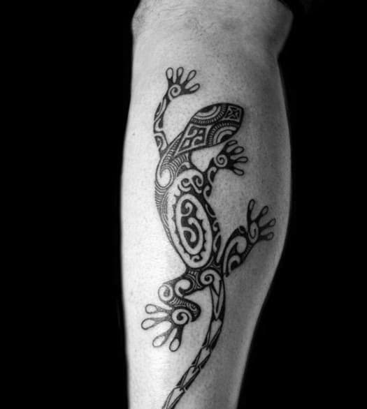 Tribal gecko tattoo on calf featuring detailed spiral and geometric patterns, bold lines, and stylized feet.