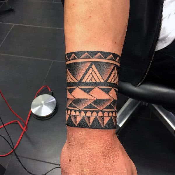 Forearm with a bold geometric black ink tattoo featuring triangles and lines