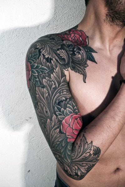 This tattoo features intricate tribal designs combined with red roses and green leaves, creating a bold and stylized sleeve