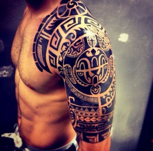 Man with intricate black tribal tattoo covering shoulder and upper arm