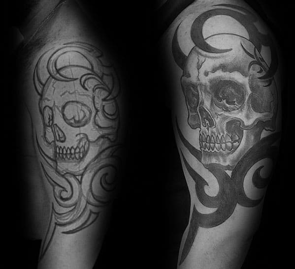 Tribal skull tattoo in progress on upper arm, featuring swirling black patterns and a detailed realistic skull with strong shading.