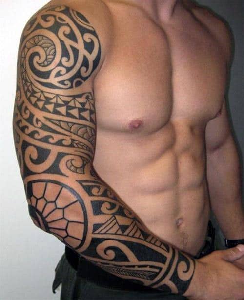 A shirtless man with a detailed black tribal sleeve tattoo