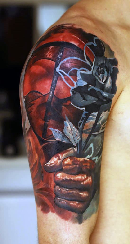 Colorful tattoo depicting a hand holding a black rose on a person's upper arm