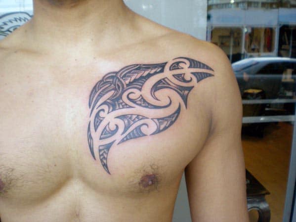 Person's chest with intricate black tribal tattoo design on left shoulder