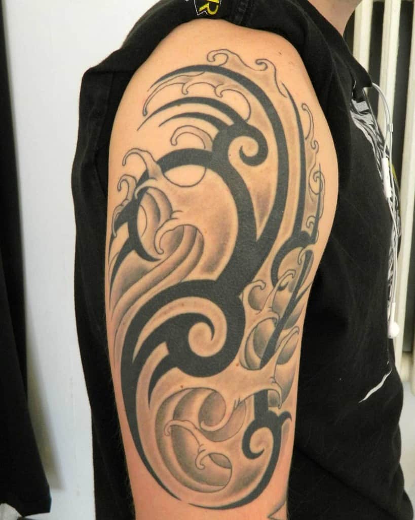 Arm with an intricate black tribal tattoo design covering the shoulder and upper arm