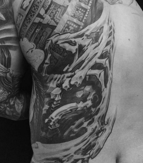 Black and grey biomechanical tattoo extending from the arm to the ribs, featuring exposed gears, skeletal structures, and intricate machinery.