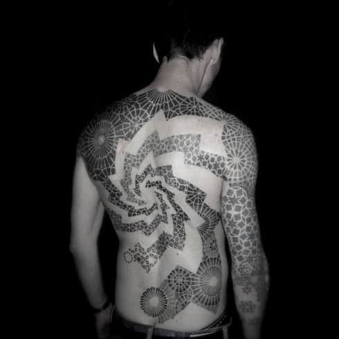 Full-back and arm tattoo featuring intricate geometric patterns forming spirals and mandala-like shapes in a bold blackwork style.
