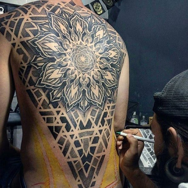 Intricate full-back tattoo featuring a large symmetrical mandala with layered petals and a geometric triangle frame filled with dotwork patterns.