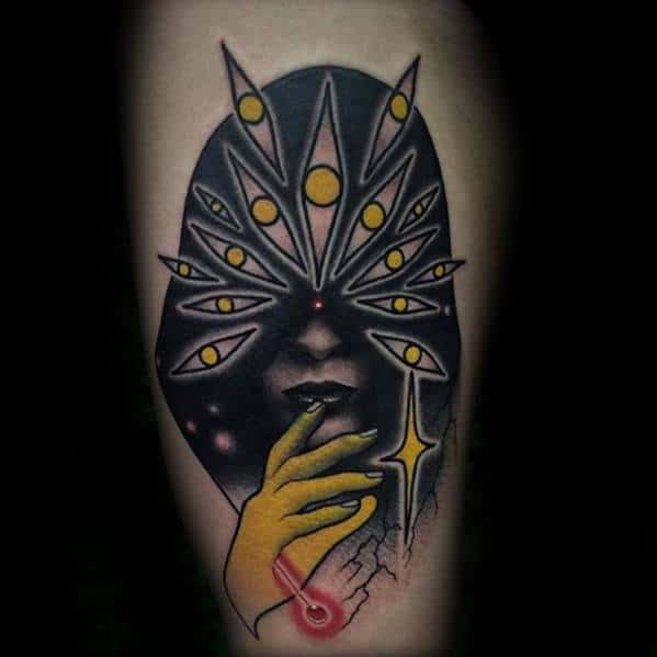 Surreal tattoo of a mysterious face shrouded in black, with multiple eye-like shapes radiating from the head and a glowing yellow hand touching the lips.