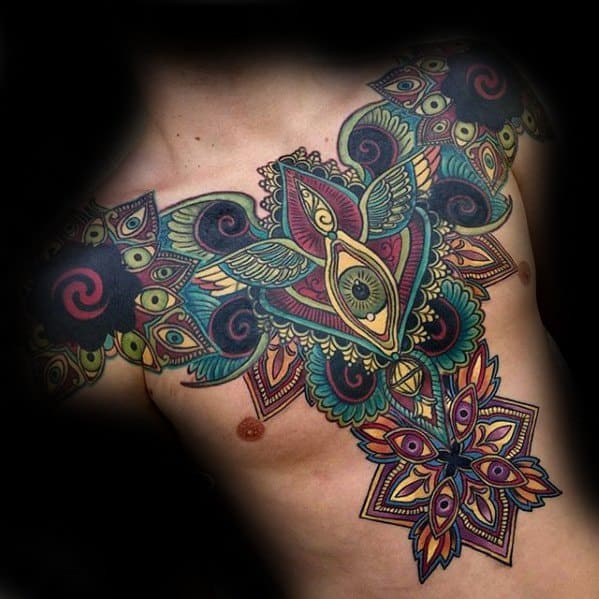 Ornate chest and torso tattoo with vibrant symmetrical patterns, mandala elements, and all-seeing eyes in a bold tribal style.
