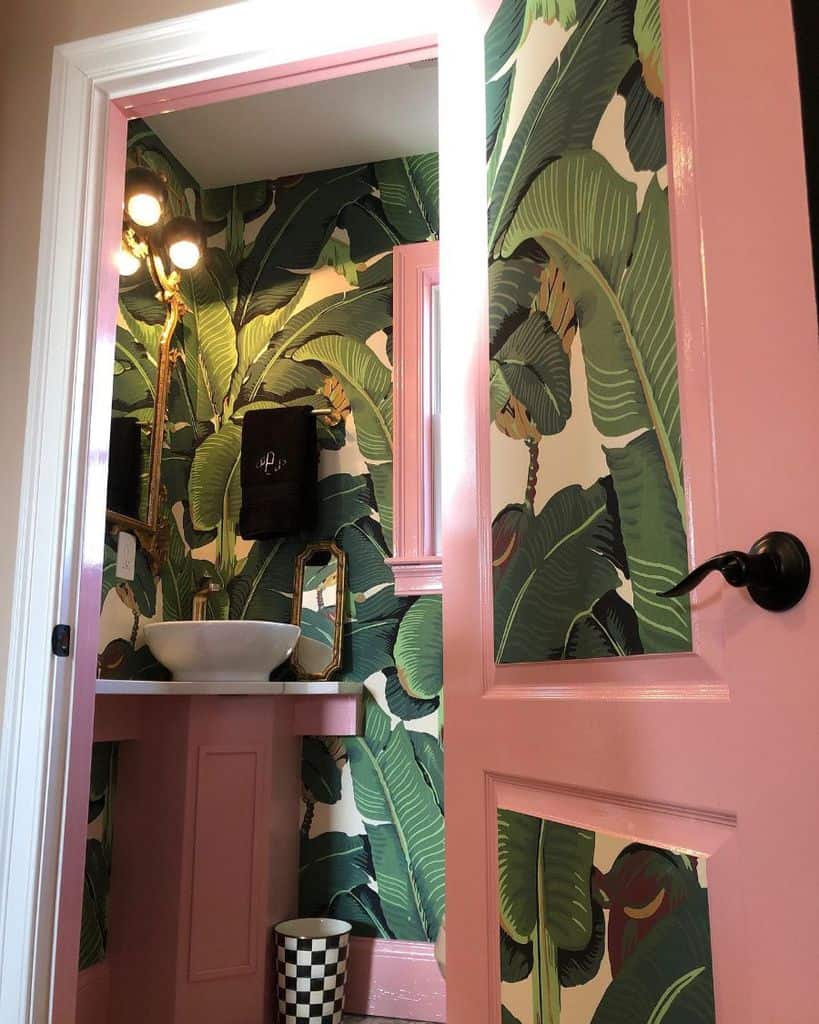 Bathroom with tropical palm wallpaper, pink accents, and white vessel sink.