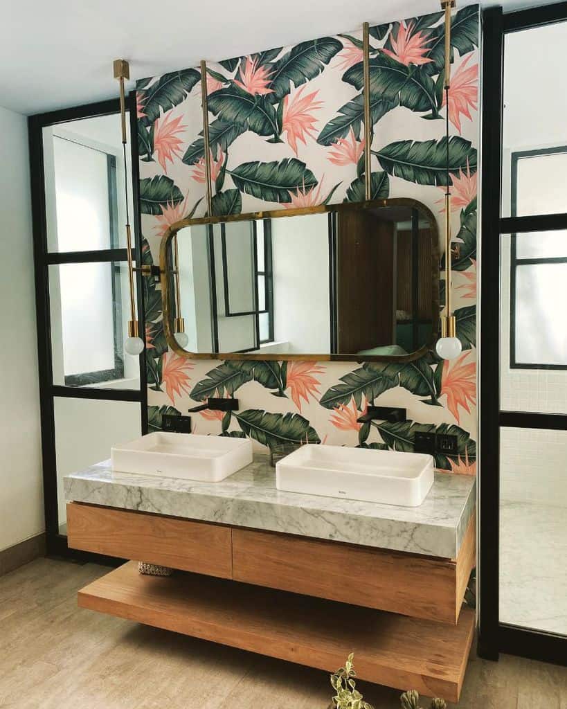 Bathroom with tropical wallpaper, wood vanity, marble countertop, and double sinks.