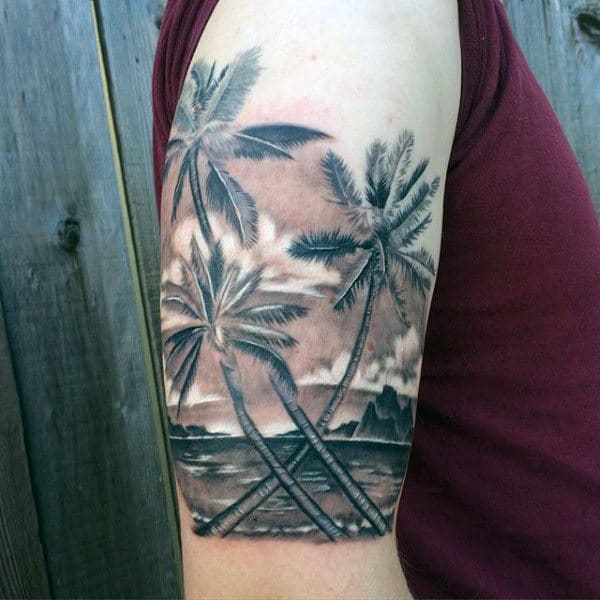 Palm tree tattoo on upper arm, depicting an ocean scene in black and gray ink