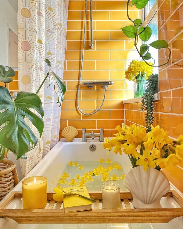 Bathroom showcasing bright yellow tiles, a tropical shower curtain, lush plants, and cheerful daffodil accents.