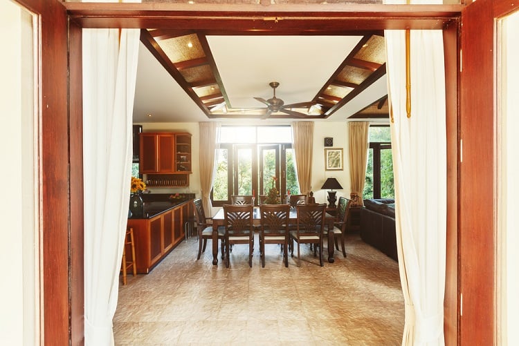 The ceiling features a high, wooden design with exposed beams, adding a rustic and airy feel to the tropical villa's spacious living area