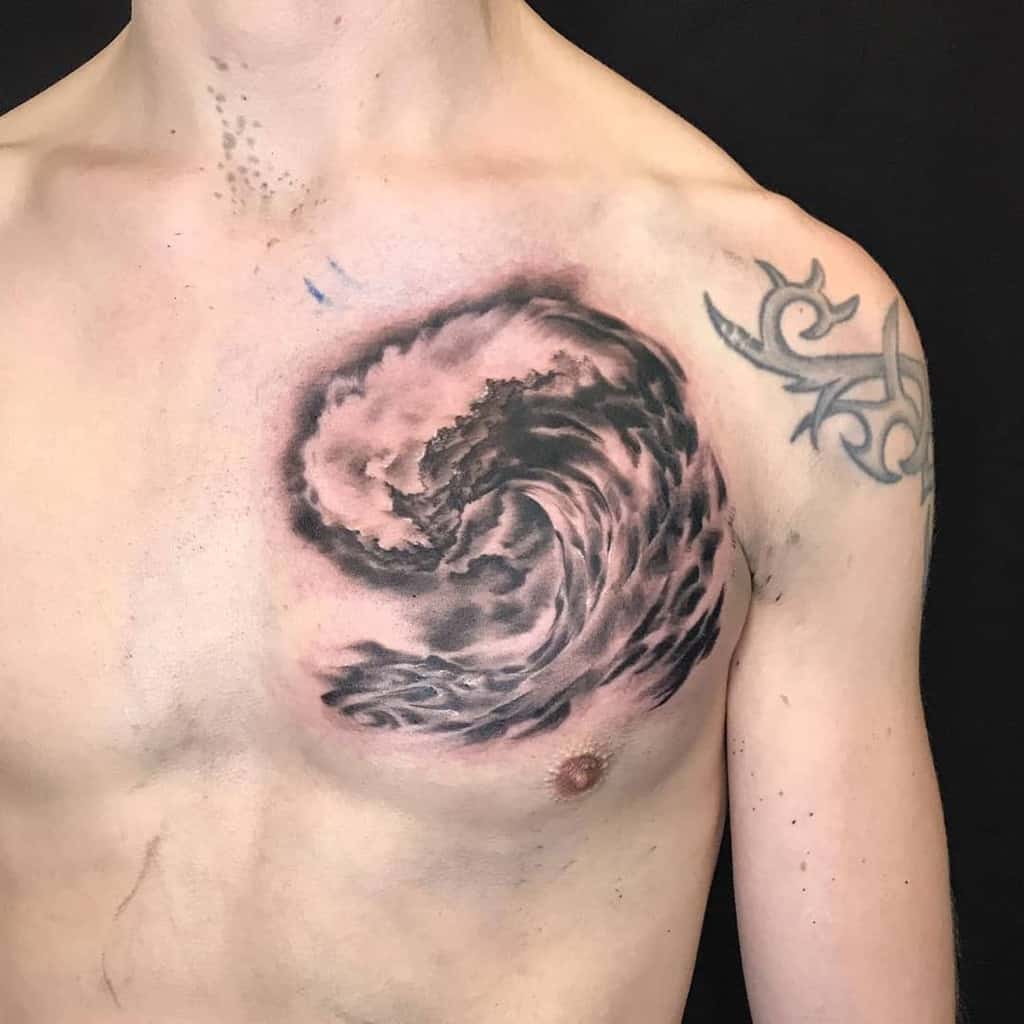 Realistic black and grey tattoo of a powerful ocean wave with detailed shading, creating a dynamic and dramatic effect