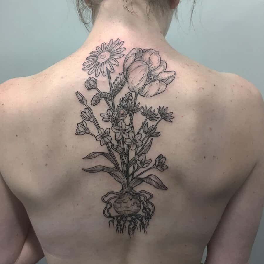 Center back tattoo large black and grey tulips and daisies with roots